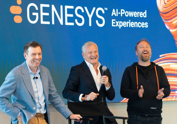 Three senior Genesys staff standing together smiling on stage at a conference.